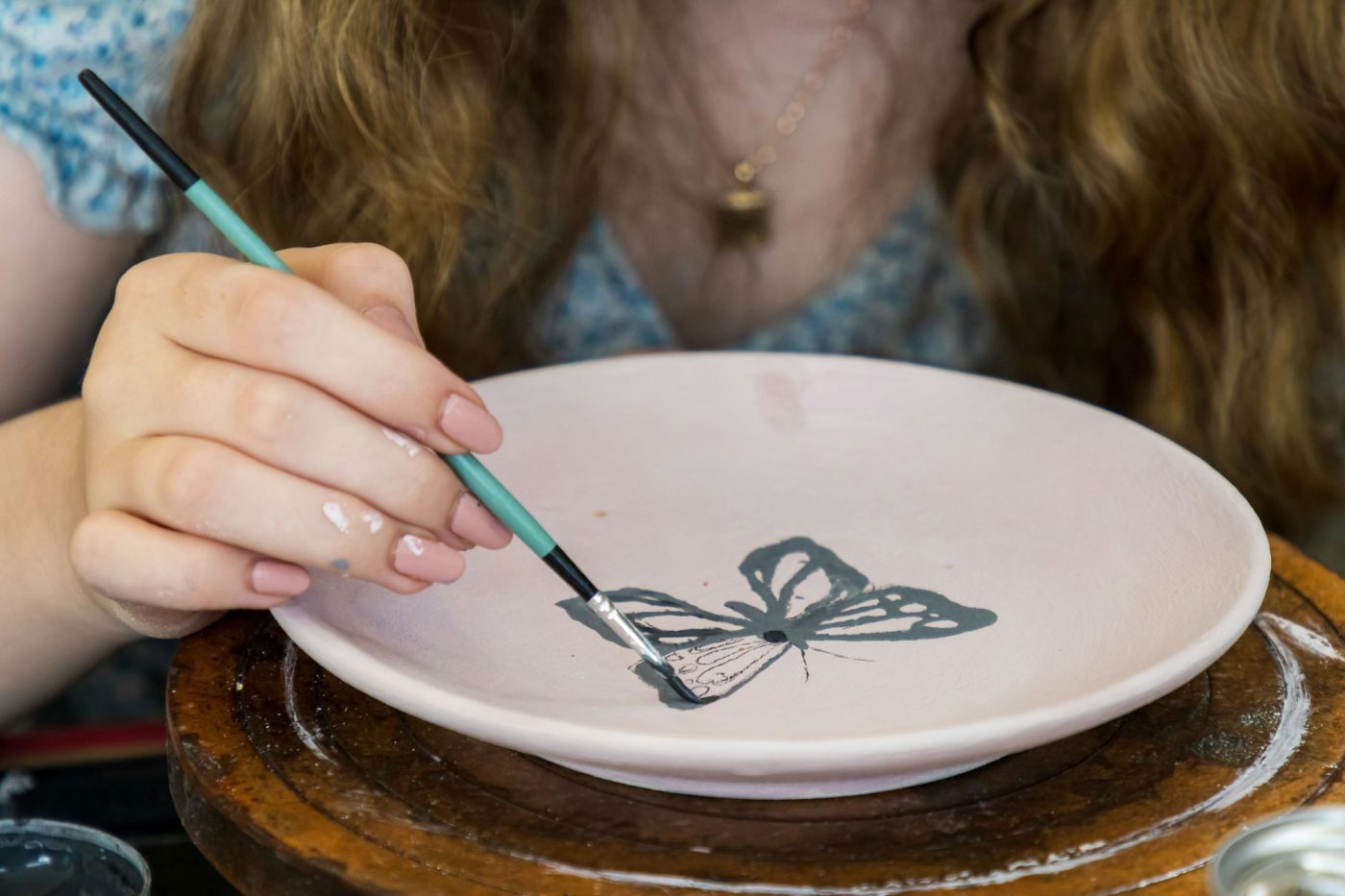 Main peignant un motif sur une assiette en céramique